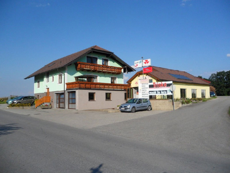 Aussenaufnahme unserer Werkstatt mit Blick auf den Parkplatz und die Werkstatthalle